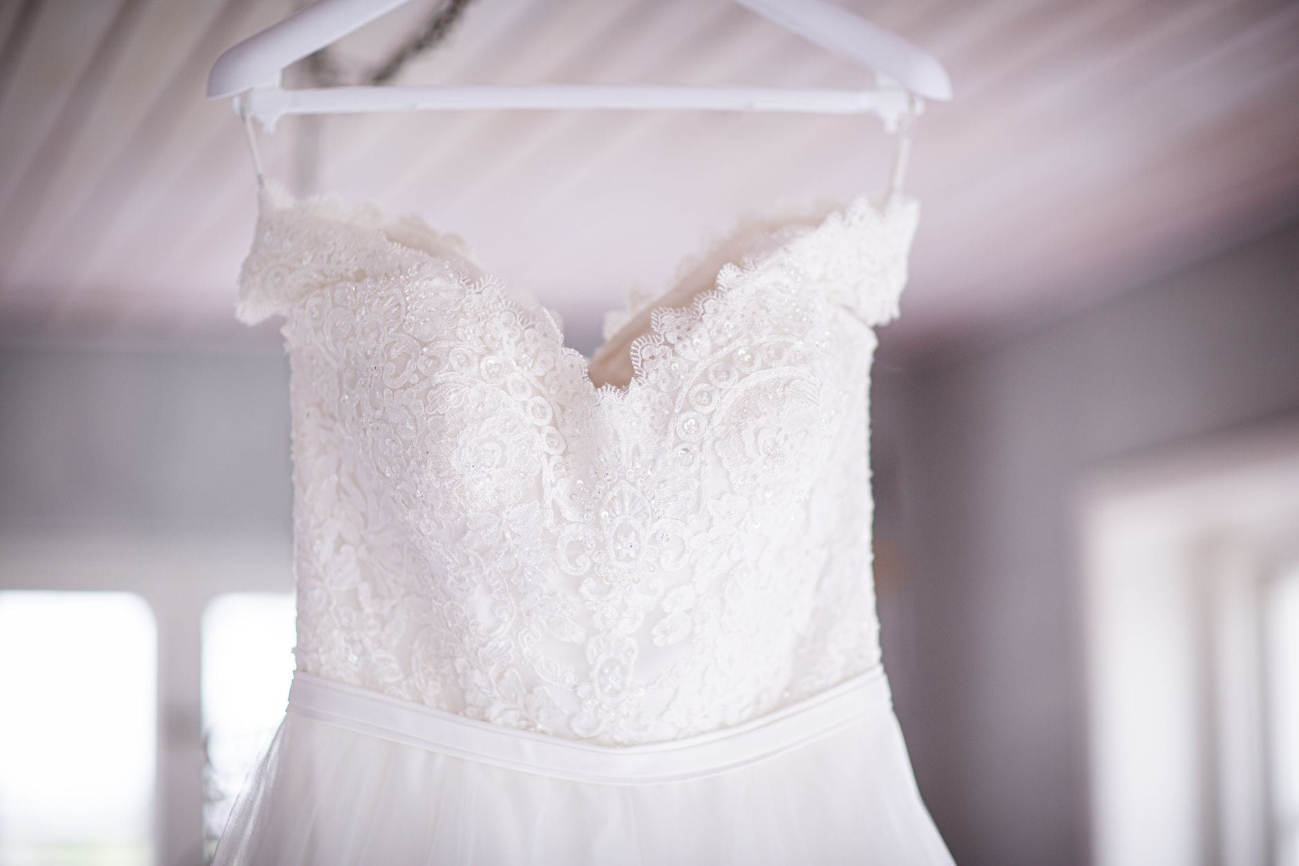 Brautkleid auf einem Bügel im warmen Licht des Studios